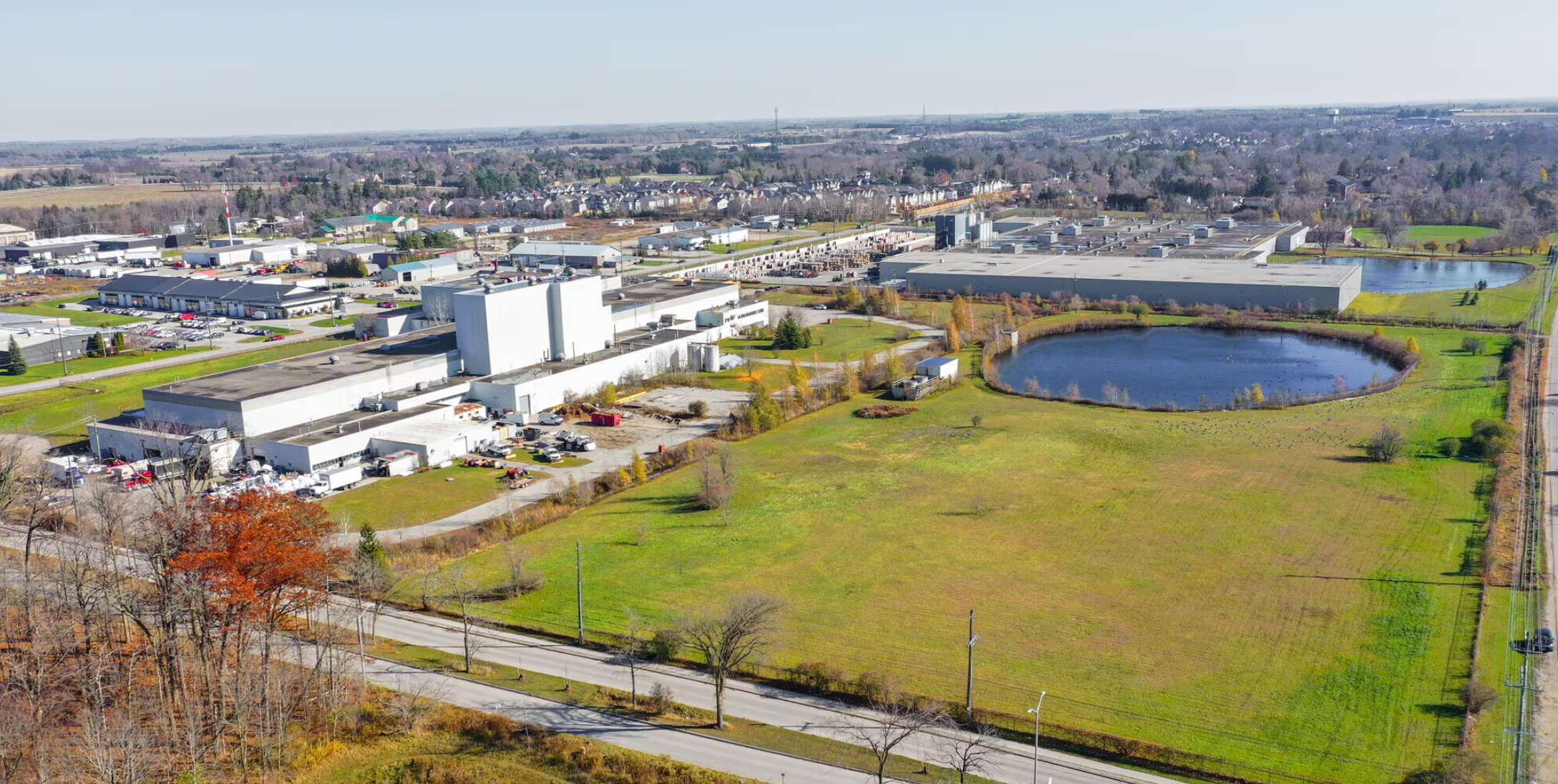 Aerial photo of the real 865 Gartshore parcel: the industrial building, the round cooling pond, open fields and surrounding town