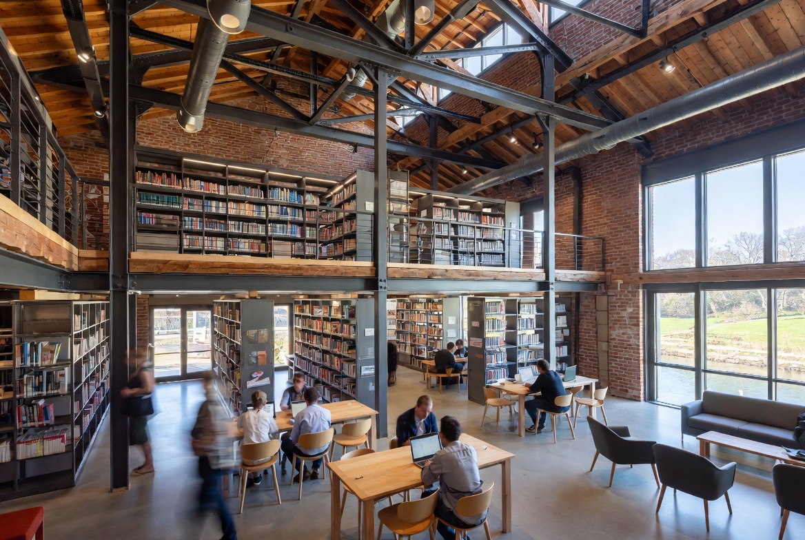 Library interior inside the mill - exposed brick, steel beams, double-height bookshelves