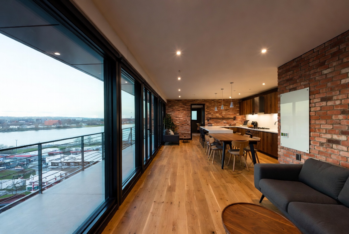 Loft-style residence interior with brick wall, wood floors, and river view